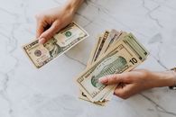 特写镜头聚焦于大理石背景上清点的美元纸币，突出金融主题