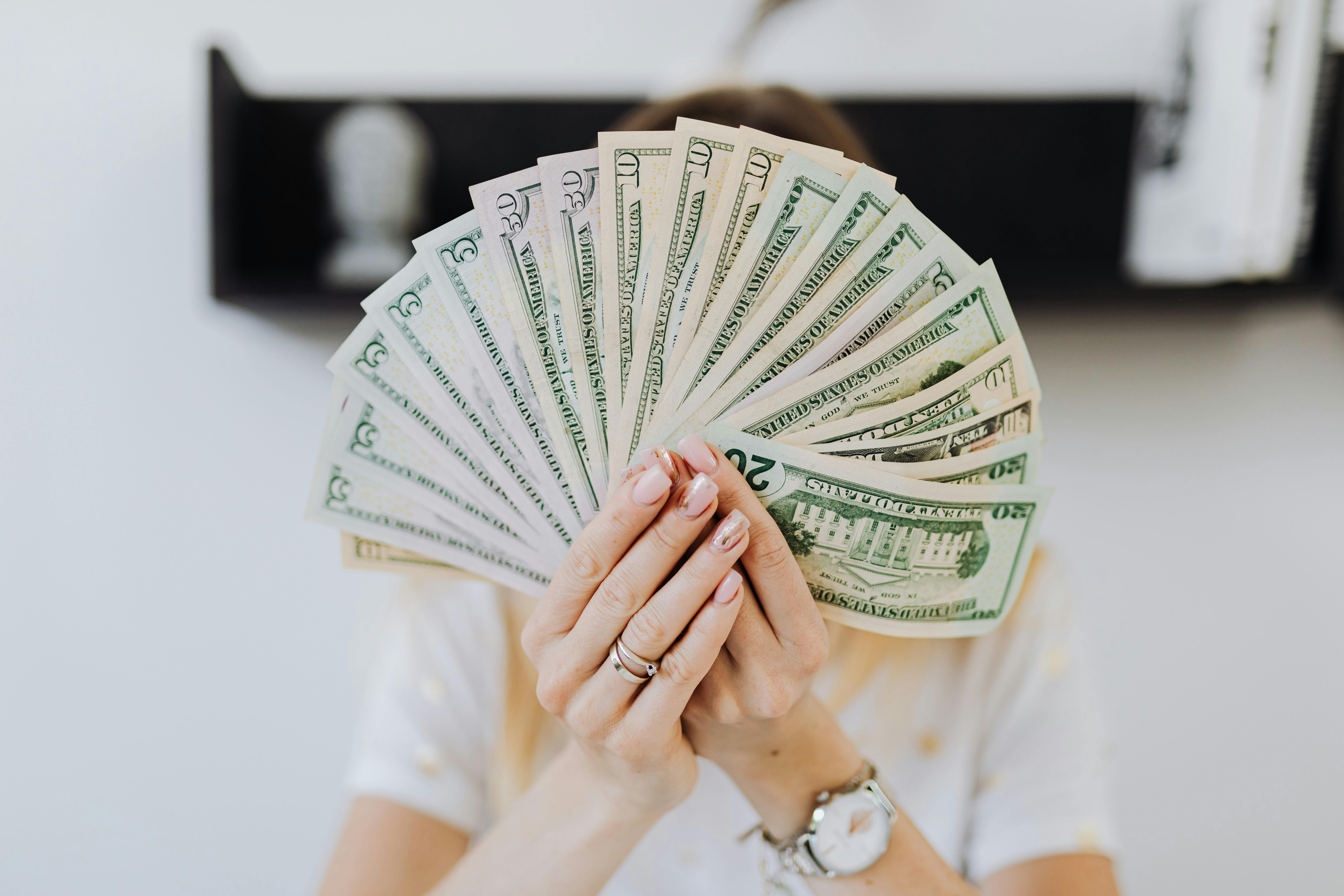 person holding fan of us dollar bills