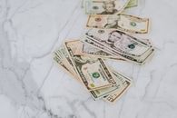 大理石表面铺着一堆美元纸币，象征着财富与金融