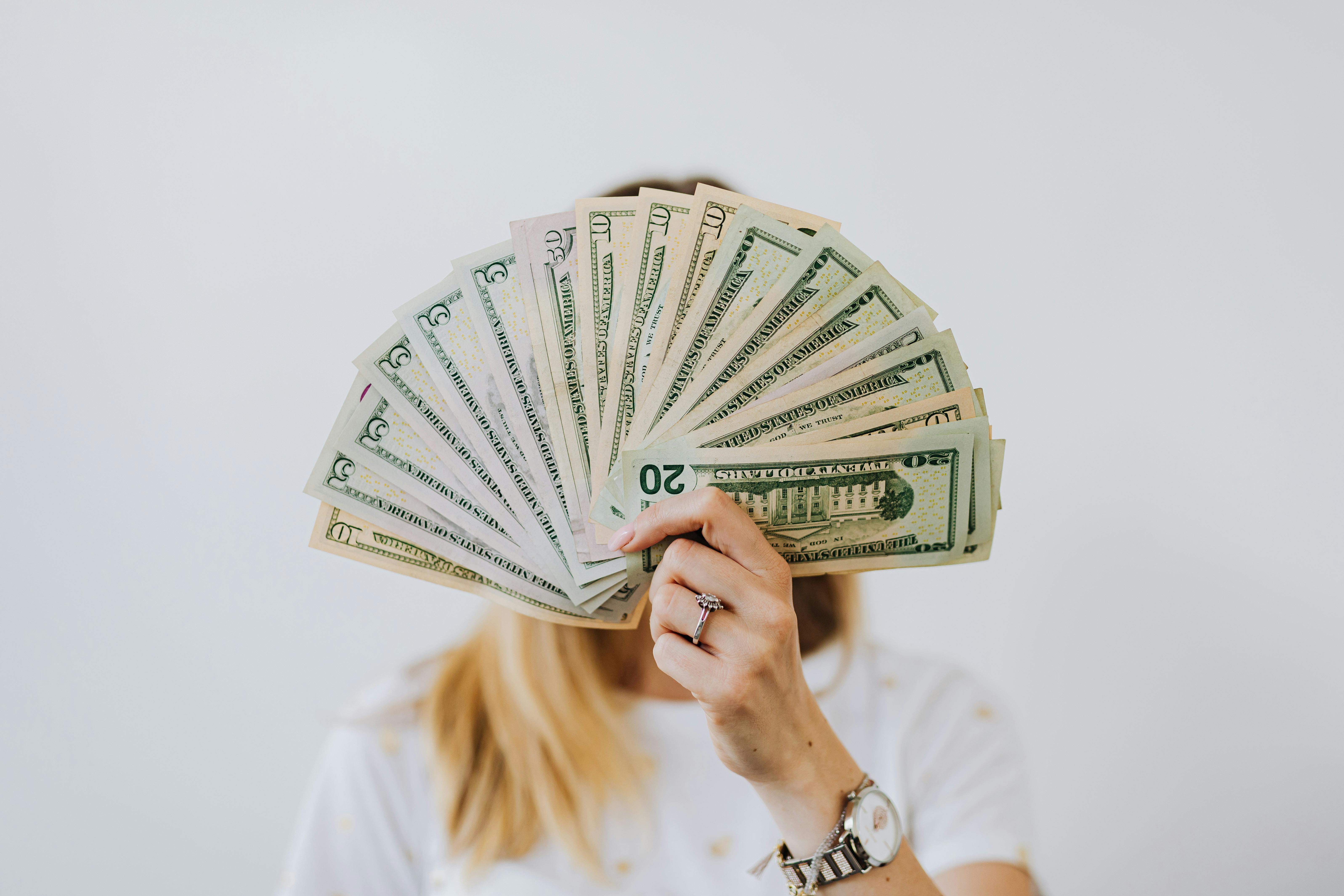 woman holding fan of us dollar bills