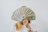 特写：一个人在中性背景下拿着一把美钞扇子