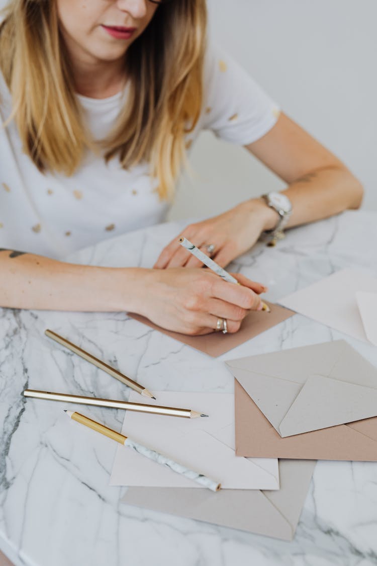 Woman Sitting At Table Writing On Paper Postcards