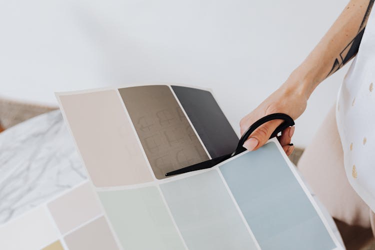 Woman Cutting Paper With Paint Samples