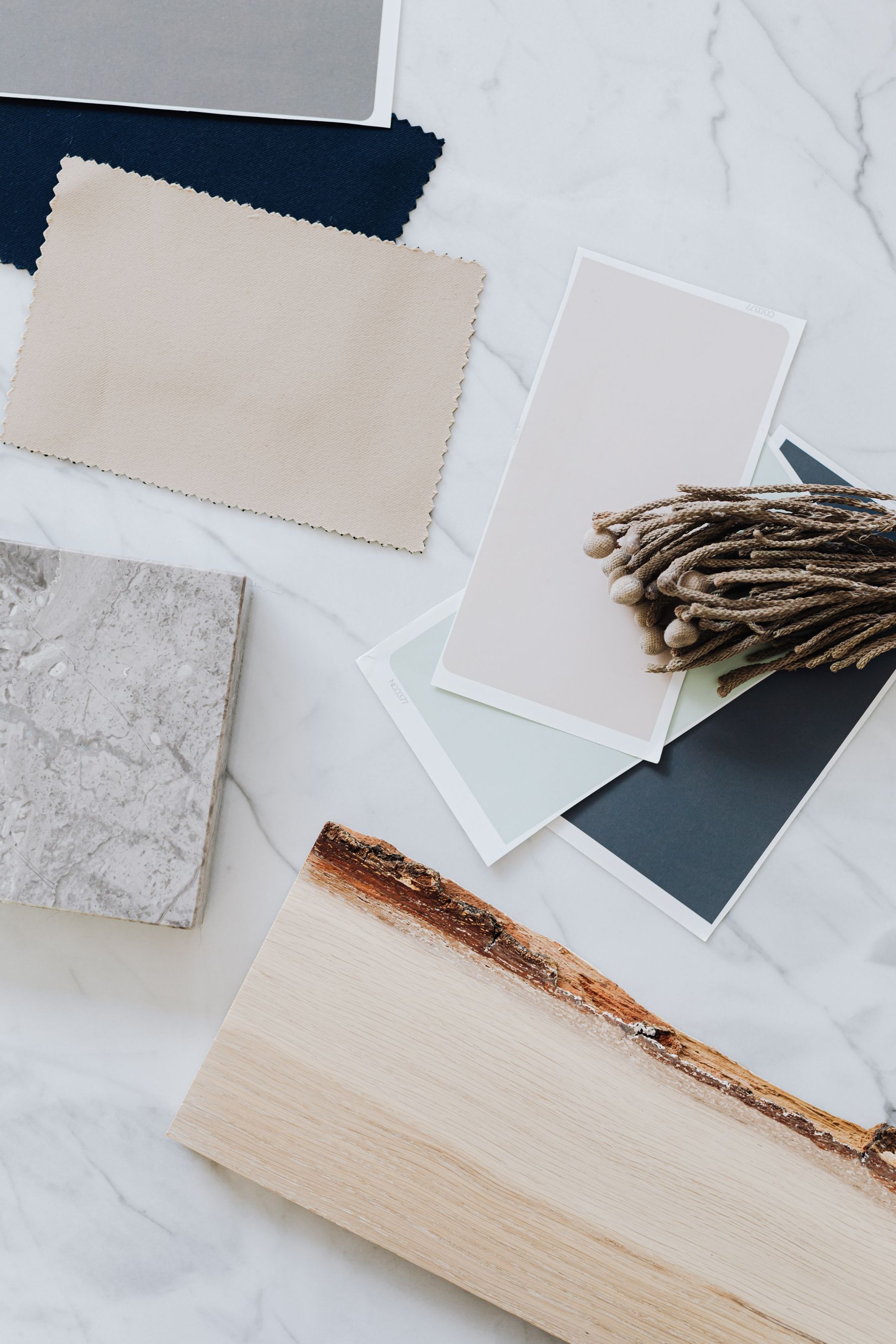Warm neutral material samples including wood stone textiles and paint arranged for design coordination