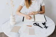 Woman Writing in Notebook on Table