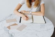 Woman in White Shirt Writing on White Paper