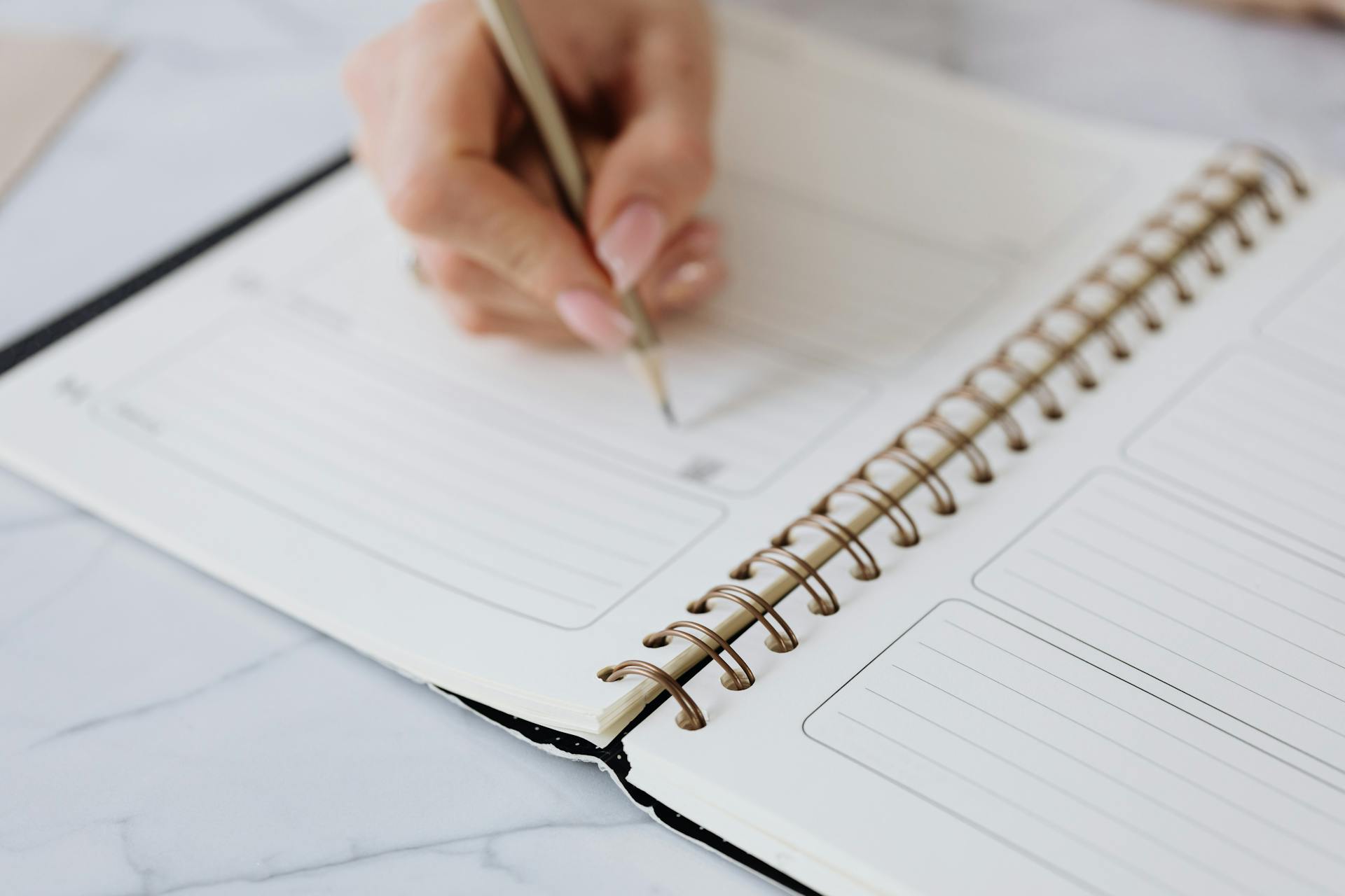 A Person Writing on a Notebook