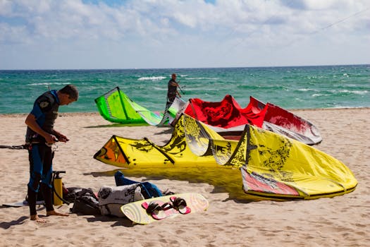 Kiteboarders prepare equipment on Pompano Beach in Florida under a sunny sky.