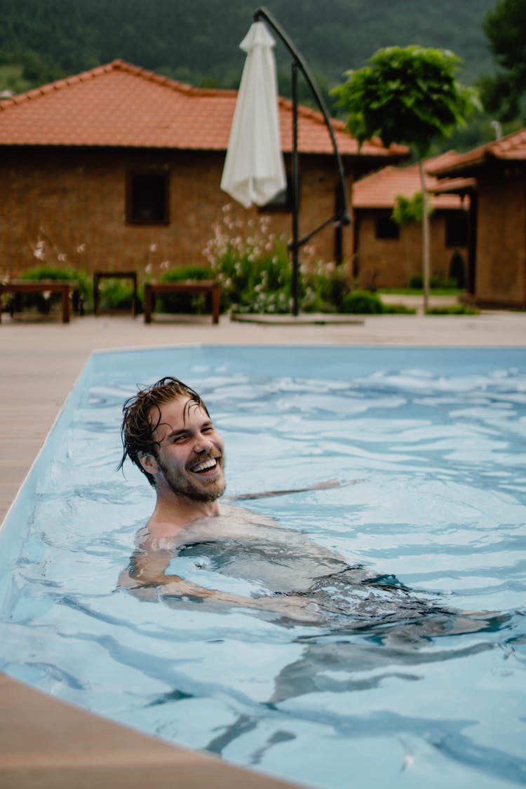 Smiling Man Swimming In Pool Of Resort