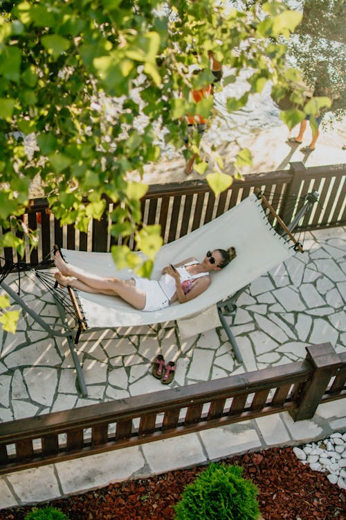 Woman lying on hammock under tree in sunny day