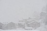 Severe scenery of remote rural village houses covered with thick layer of snow during intense snowstorm on cold winter day