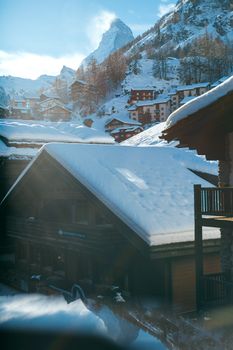 在冰冻丘陵地带，一座屋顶积雪的偏远村庄小屋，在冬季的明媚阳光下显得风景如画