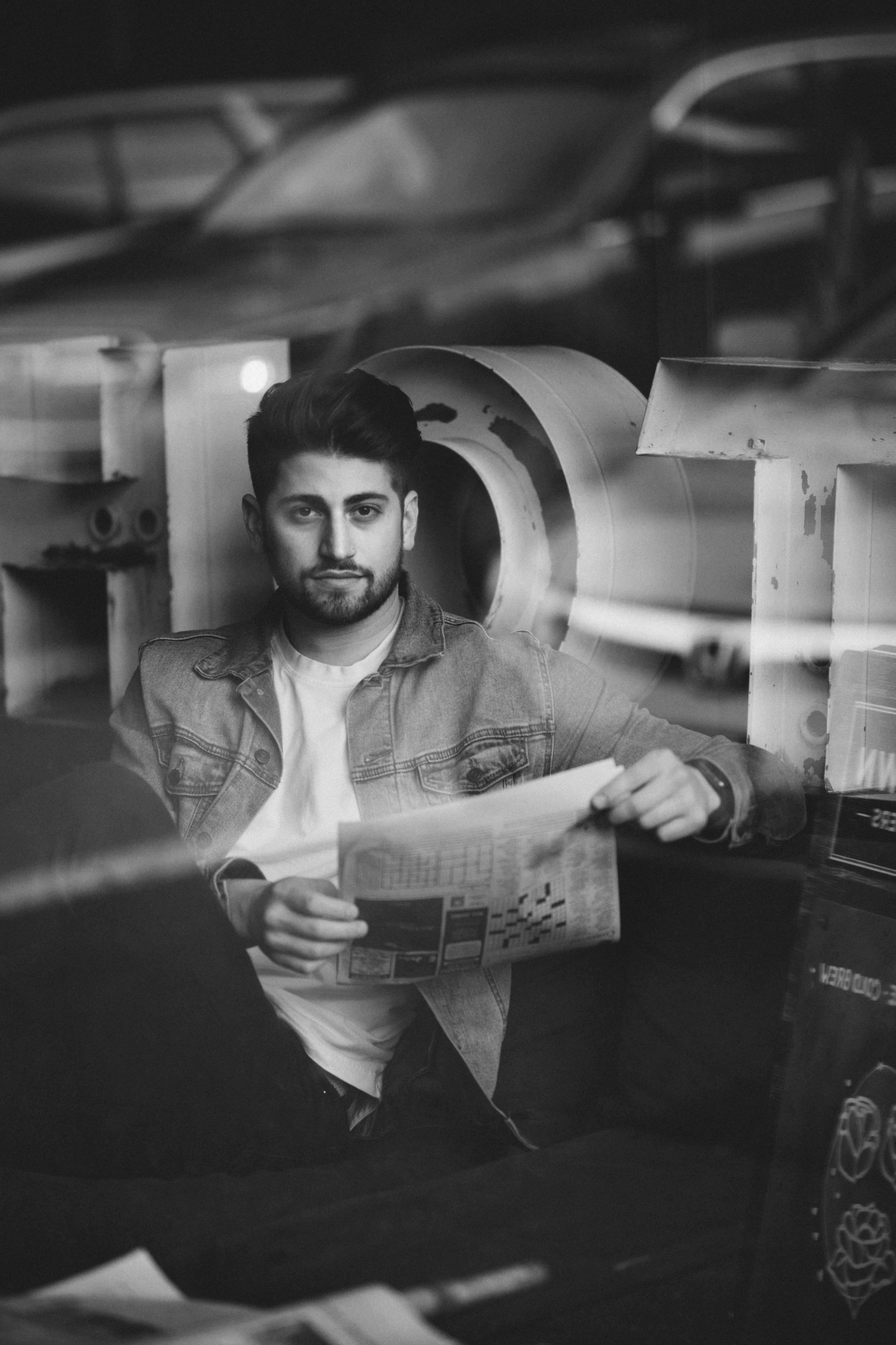 positive young man with newspaper sitting on sofa