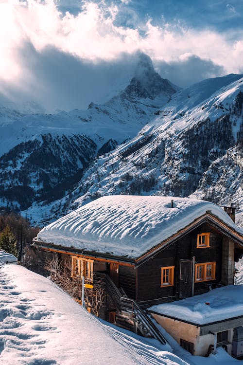 Wooden house with snow on roof in winter mountainous terrain