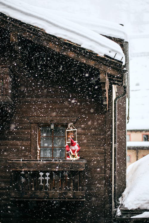 Christmas decoration placed on wooden rural house balcony during heavy snowfall on cold winter day