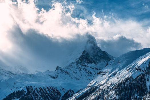 白雪覆盖的山峰在多云天空下令人惊叹，捕捉到了冬季风景的宁静之美