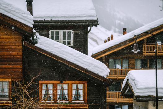 宁静的冬季降雪中，迷人的木制小屋被雪覆盖