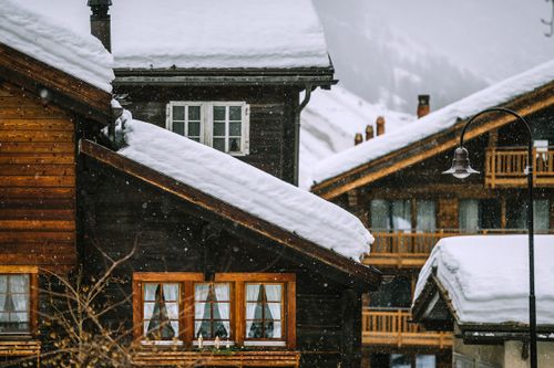 Free Exteriors of typical wooden cottages with fluffy white snow on roofs located in mountainous countryside during blizzard Stock Photo