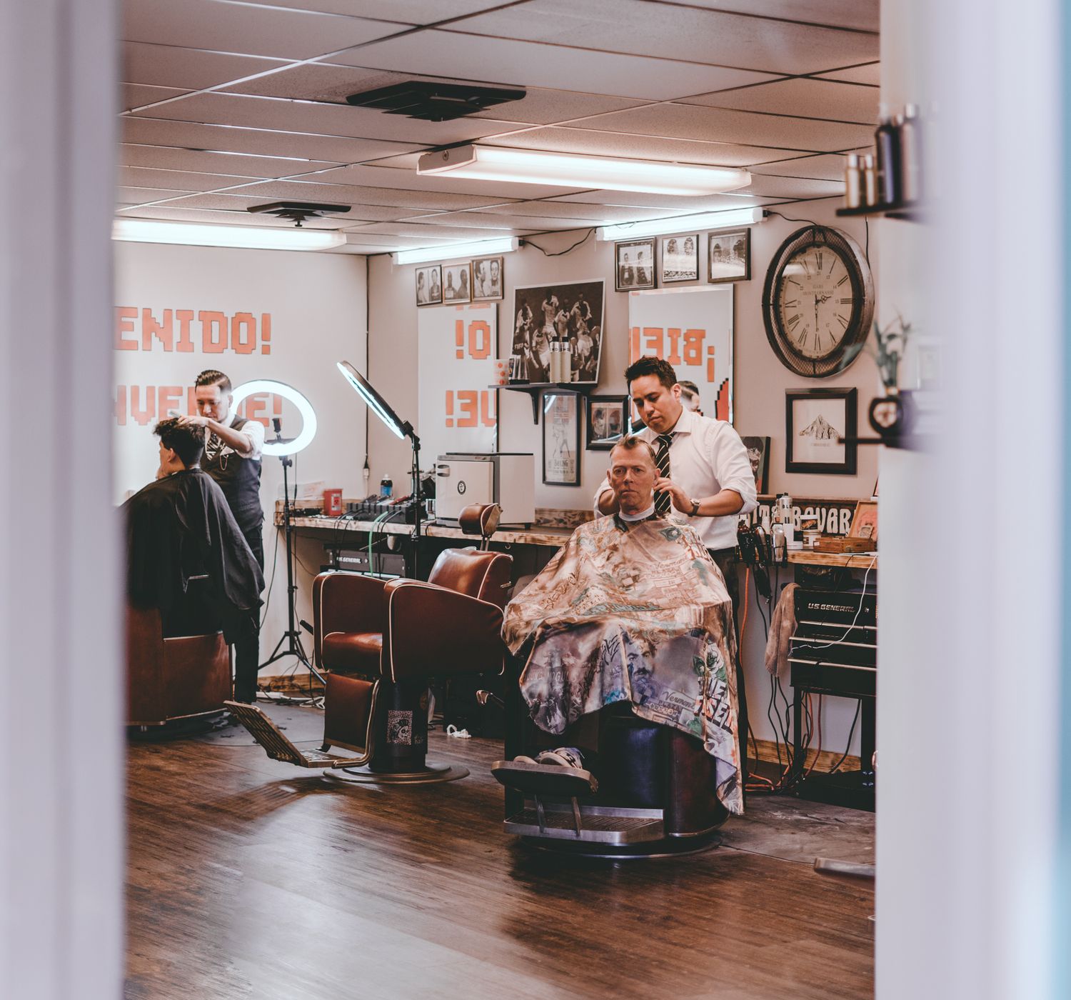 Professional barbers cutting hair of male clients sitting on chairs in traditional barbers