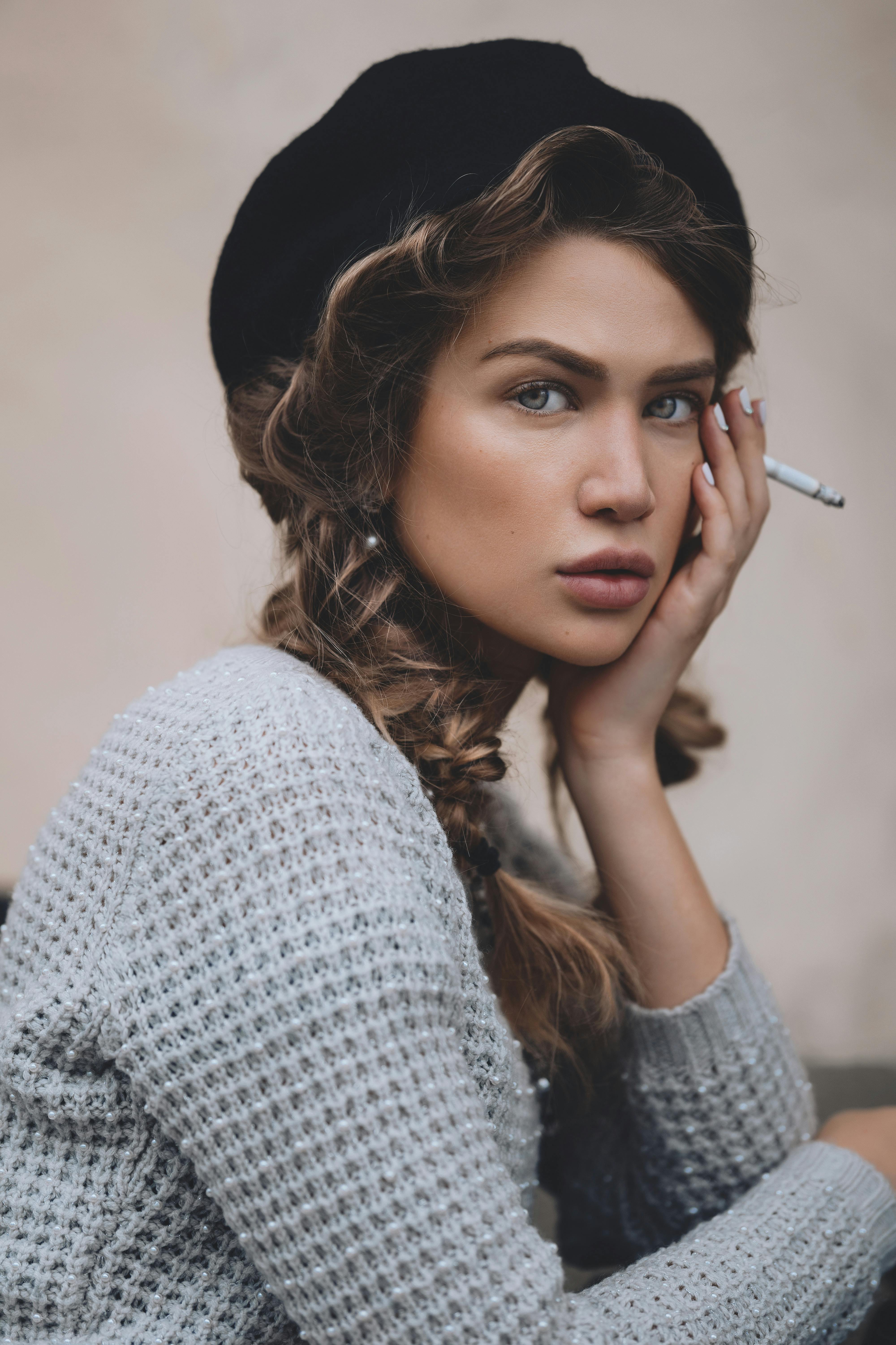 woman in beret with cigarette touching face