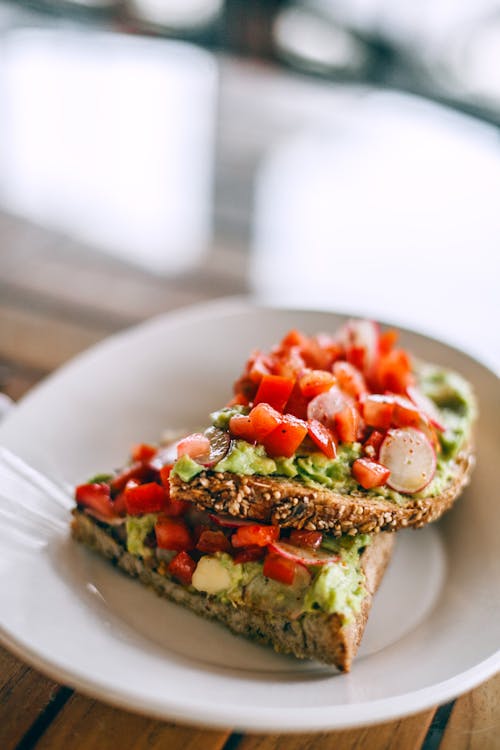 Free Delicious sandwiches with avocado and juicy tomato slices on rye bread pieces with sesame seeds Stock Photo