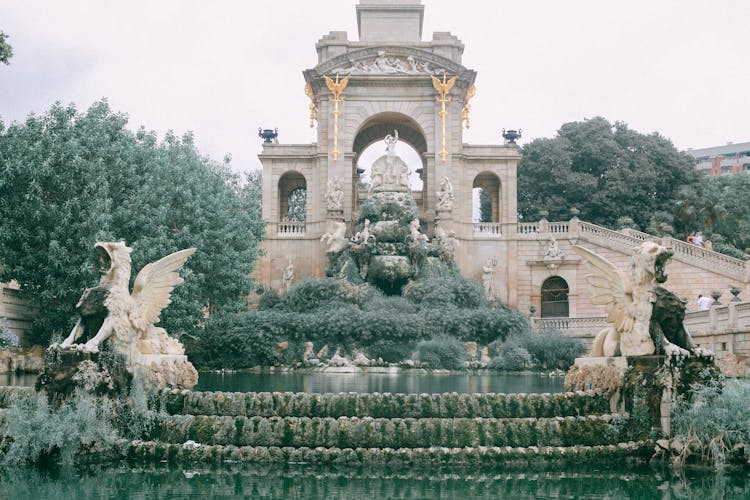 Old Stone Monument With Statues And Fountain In Garden