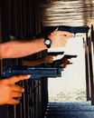 People Holding Pistols at a Shooting Range