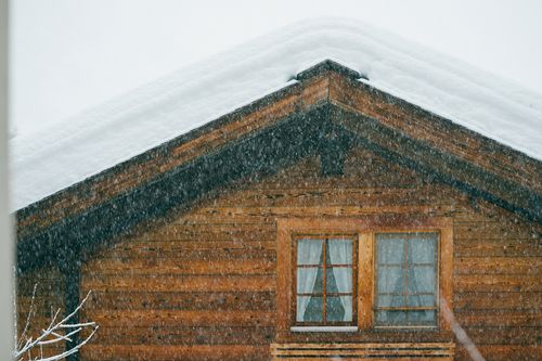 Free Through window view of old wooden house exterior under white sky during snowfall in winter in countryside Stock Photo