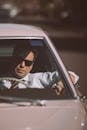Businessman in sunglasses driving retro car in town