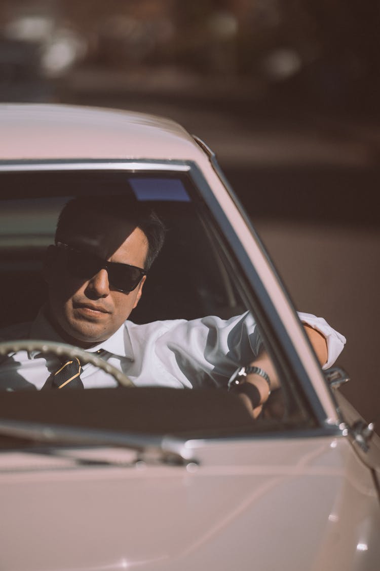 Businessman In Sunglasses Driving Retro Car In Town