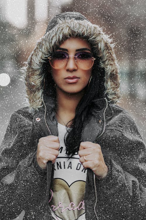 A Woman in Sunglasses Posing While Wearing a Hood