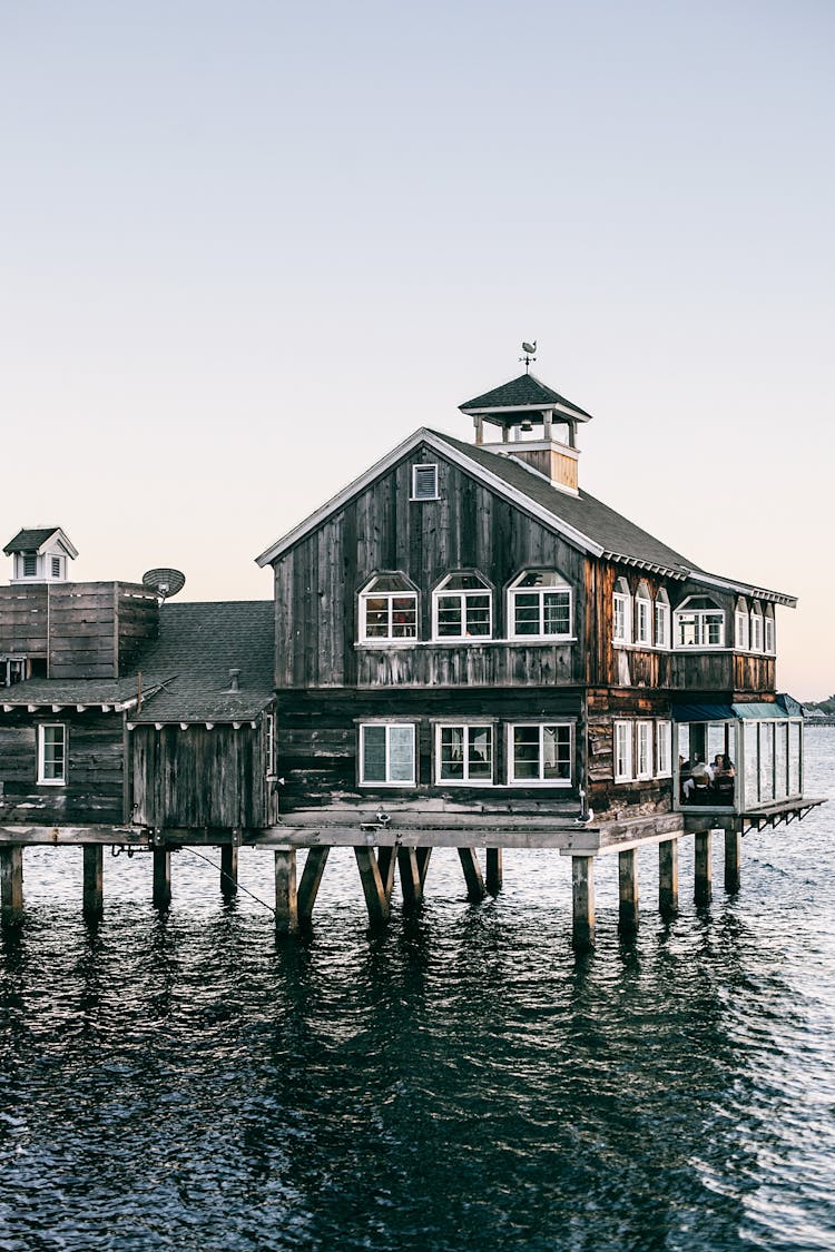 Old House On Pier In Ocean At Sunset