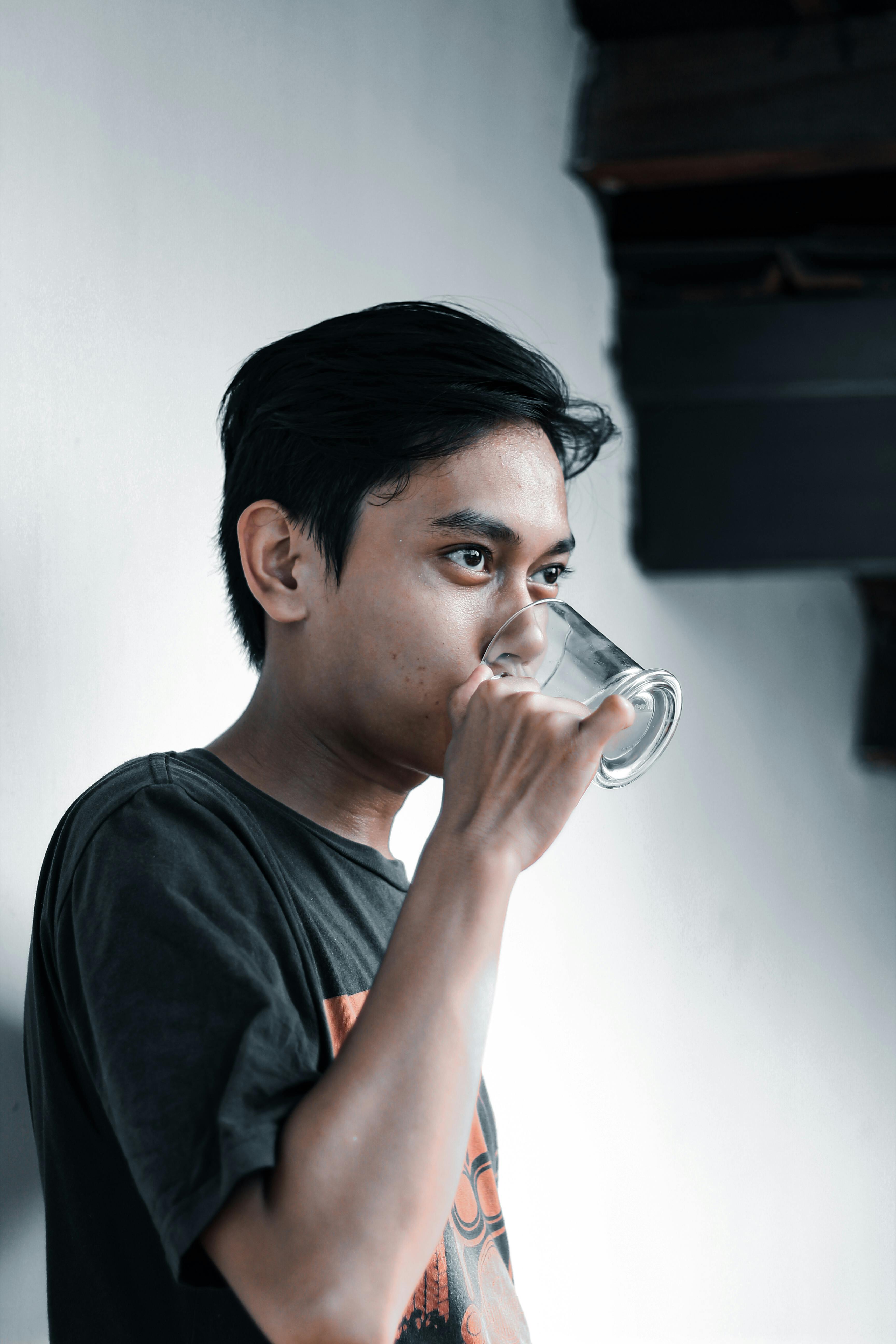 Man in a Black Crew Neck Shirt Drinking from a Clear Glass Mug · Free