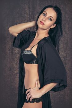 Caucasian woman in black lingerie poses gracefully indoors, exuding confidence and style.