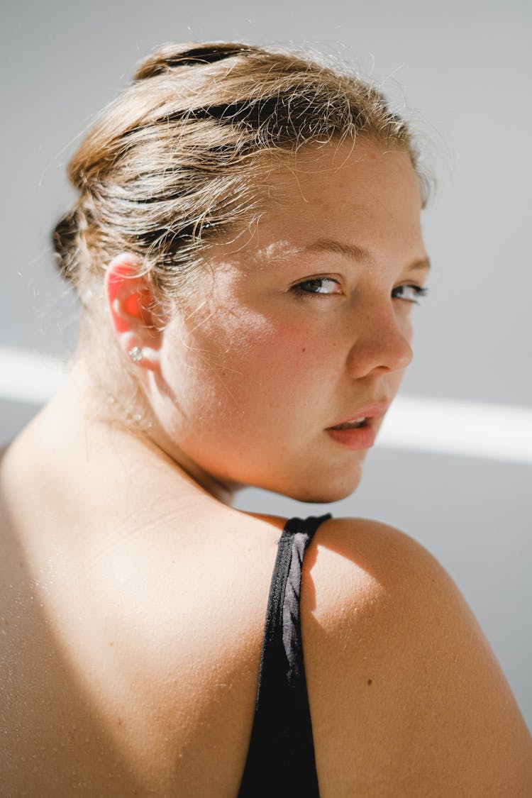 Photo Of A Young Woman Sitting In Sunlight And Looking Over The Shoulder