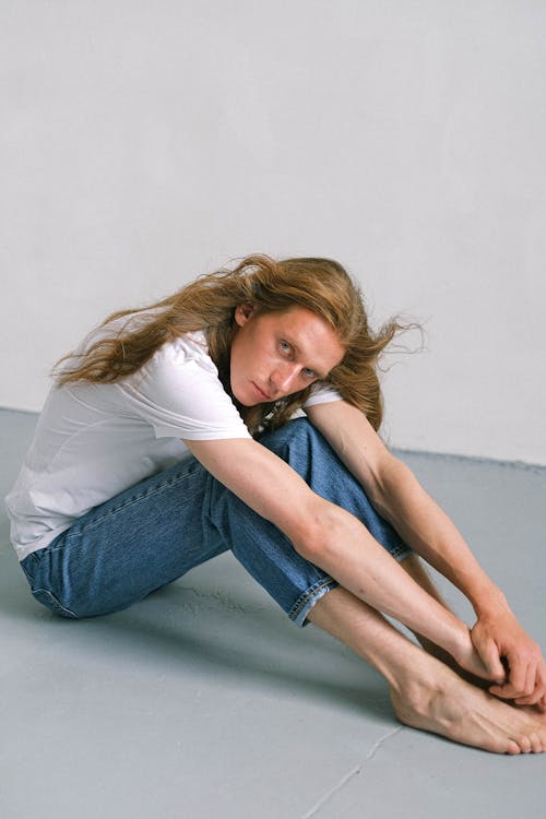 Serene androgynous man sitting on floor