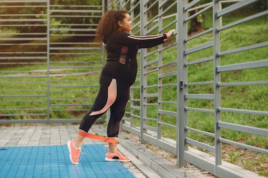 A woman exercising outside using an elastic band for a leg stretch on a sunny day.
