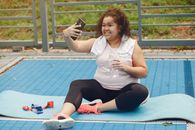 Woman in White Shirt and Black Pants Sitting on Blue Mat