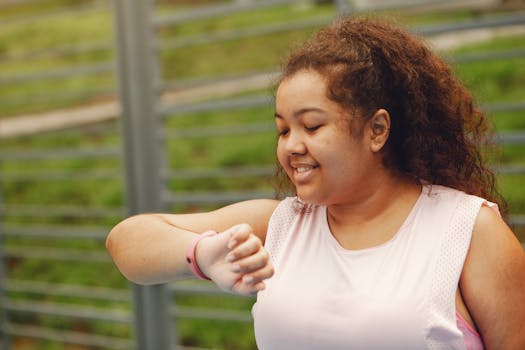 Happy woman with curly hair smiling and checking her smartwatch outdoors.