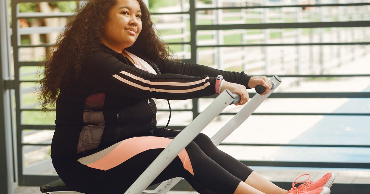 Smiling woman working out on a rowing machine on a bright covered terrace