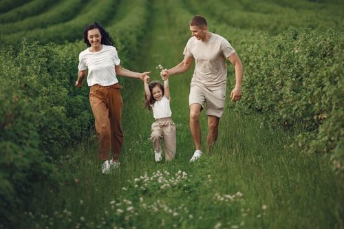 Free Joyful family enjoying a fun day outdoors in a green field, epitomizing togetherness and happiness. Stock Photo