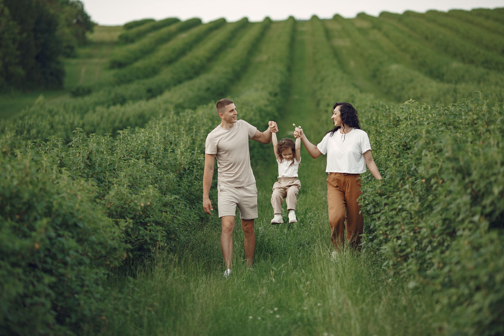 A happy family walking in a lush, green rural field together.