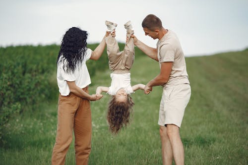 Parents Holding Their Child Upside Down and Smiling 