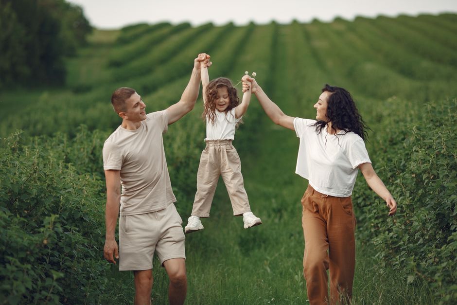Momento familiar alegre en un campo verde durante el verano, capturando amor y diversión.