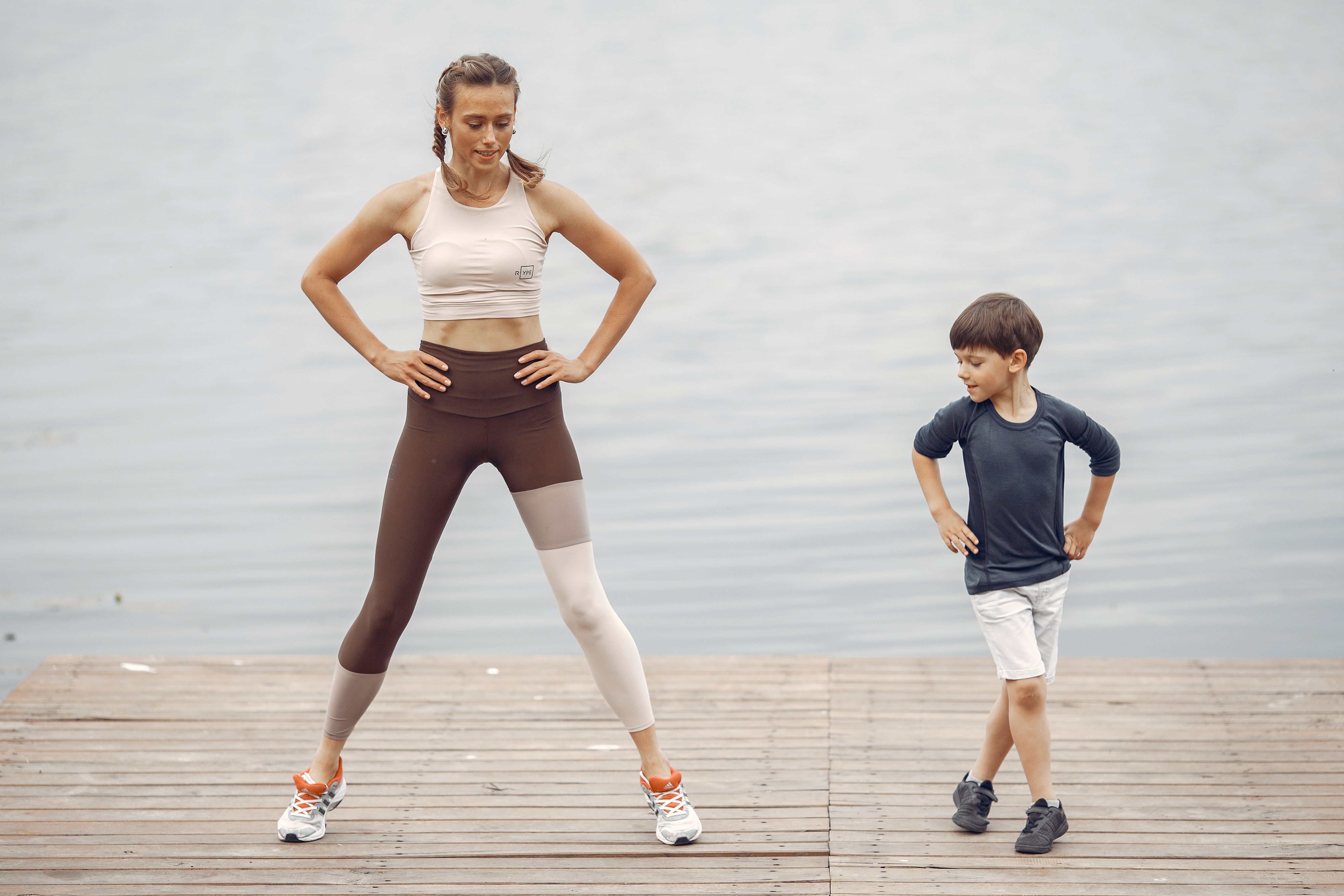 A mother and son exercising together on a wooden pier by the lake, enjoying fitness and fun.