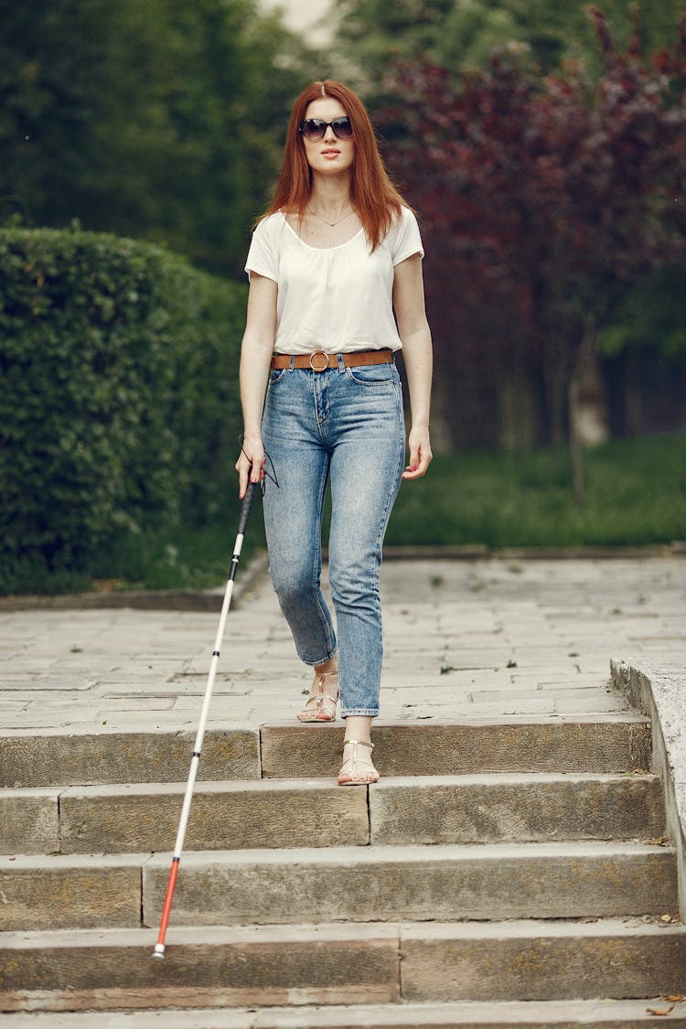 Shallow Focus Of A Blind Woman Walking Down Stairs With Her Cane