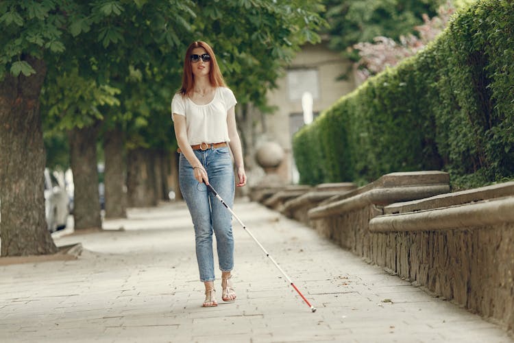 Blind Woman Walking On The Sidewalk With Her Cane