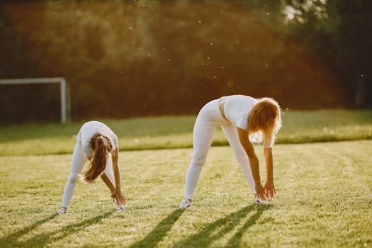Two girls stretching on a sunny day in a green field, preparing for exercise.