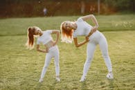 阳光明媚，一对母女穿着运动服在草地上伸展身体