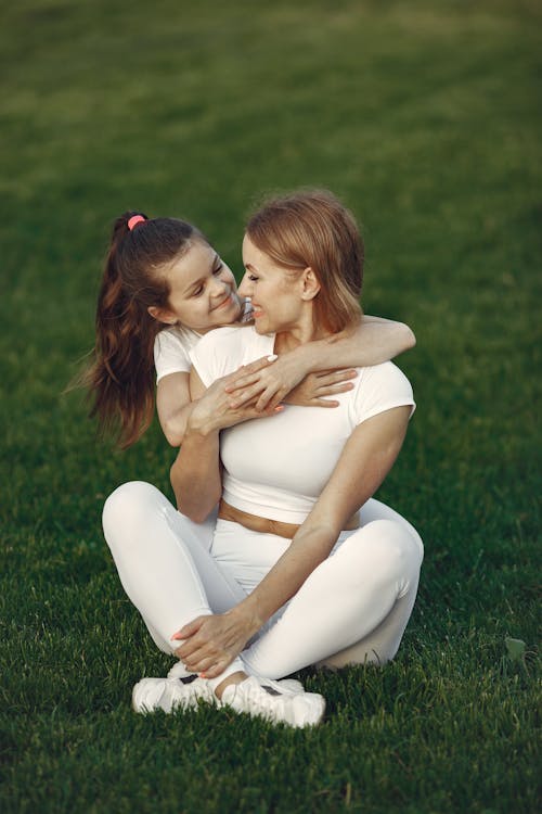 Mother and Daughter Sitting on Grass Happily